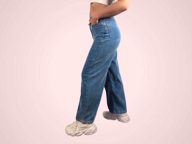 May include: Light blue corduroy pants with a straight leg design. The pants have a classic five-pocket style and are worn with white sneakers. The corduroy fabric has a subtle texture, and the pants are a medium wash.