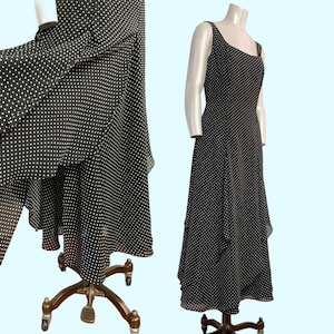 Puede incluir: Un vestido de lunares negros y blancos con falda de capas. El vestido tiene un corpiño sin mangas y un escote redondo.