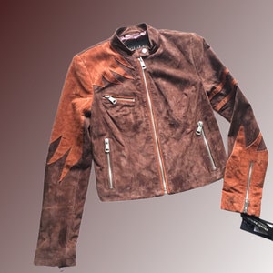 May include: A brown suede jacket with orange suede accents on the sleeves. The jacket has a zipper closure and multiple pockets.