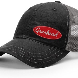 May include: Black and gray trucker hat with a red oval patch that says "Gearhead" in white lettering.