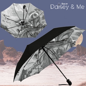 May include: A black and white umbrella with a graphic of a Mandalorian character and the text "Where I Go He Goes".