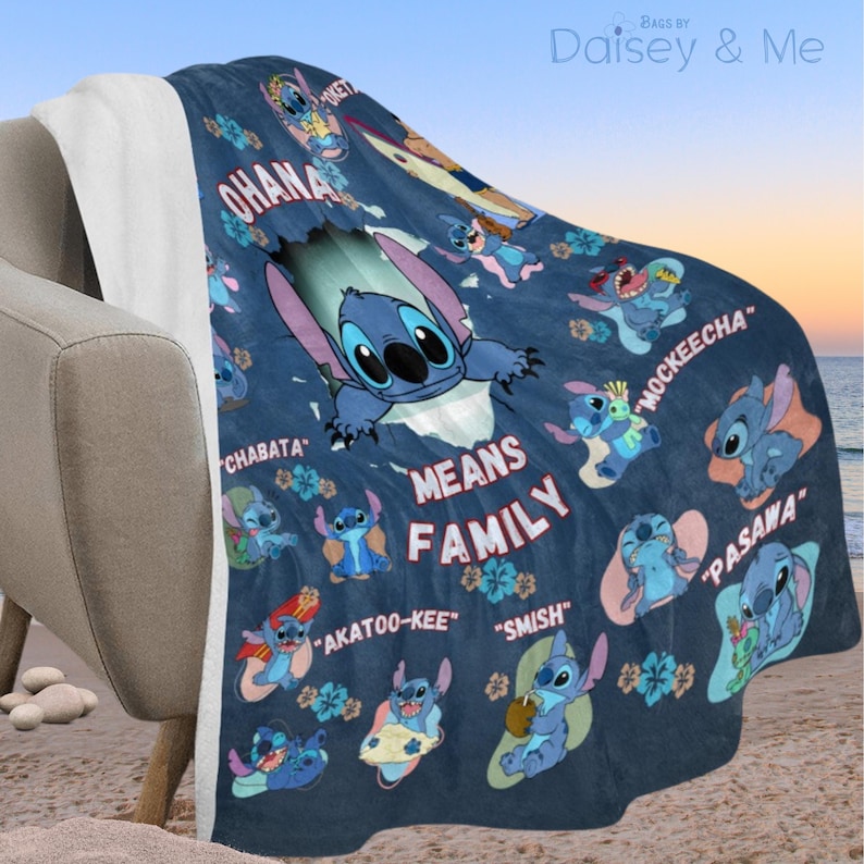 May include: A navy blue fleece blanket featuring the character Stitch from Lilo & Stitch. The blanket has Stitch illustrations and the words "Ohana Means Family" and other phrases. The blanket is draped over a chair.