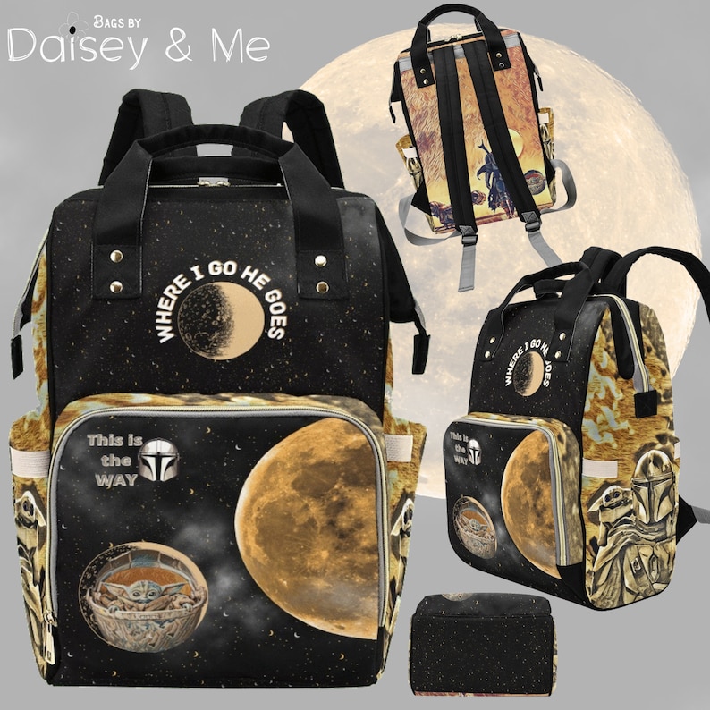 May include: A black diaper bag with a moon and stars design. The bag has a zippered pocket on the front and a large pocket on the back. The bag also has a matching zippered pouch. The text on the bag reads "Where I Go He Goes" and "This is the Way".