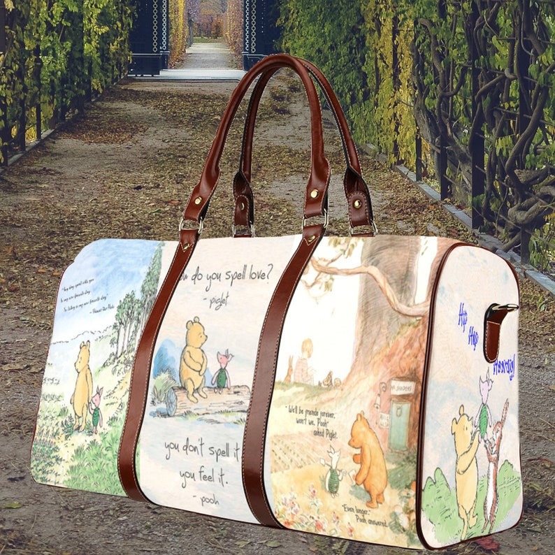 May include: A brown leather Winnie the Pooh themed travel bag with a white background and illustrations of Winnie the Pooh and his friends. The bag has a quote from Winnie the Pooh: "You don't spell it, you feel it."