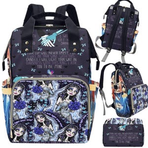 May include: A black and blue backpack with a floral pattern featuring a bride and groom. The backpack has a large main compartment and a smaller front pocket. The text "Your cup will never empty for I will be your wine with this candle I will light your way in darkness with this ring I ask you to be mine" is printed on the front of the backpack.