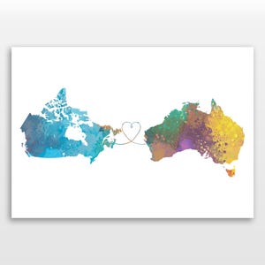 May include: Watercolor print featuring the maps of Canada and Australia connected by a heart-shaped line. The Canadian map is blue and teal, while the Australian map is a mix of yellow, green, and purple. The background is white.