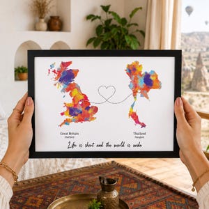 Può includere: Una stampa incorniciata con mappe ad acquerello della Gran Bretagna e della Thailandia collegate da una linea tratteggiata a forma di cuore. Il testo riporta Great Britain, Sheffield, Thailand, Bangkok e Life is short and the world is wide.