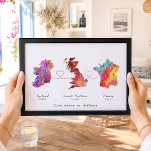 Puede incluir: Una lámina enmarcada con mapas en acuarela de Irlanda, Gran Bretaña y Francia conectados por líneas rojas finas que forman corazones. El texto dice Ireland Dublin, Great Britain London, France Paris y Love knows no distance.