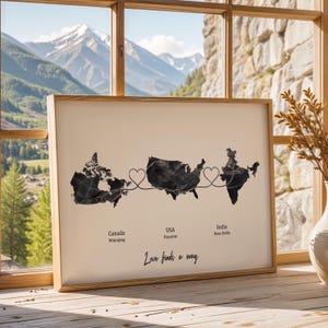 May include: Framed print featuring black map outlines of Canada, the USA, and India, connected by heart-shaped lines. The print includes the cities of Winnipeg, Houston, and New Delhi, with the text "Love finds a way" in a script font.