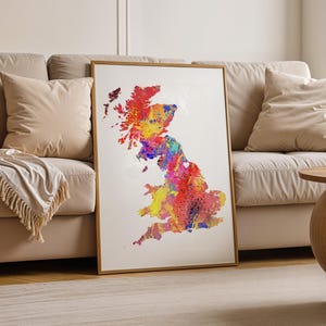 Pode incluir: Uma impressão emoldurada do Reino Unido, renderizada em um estilo aquarela vibrante. O mapa é preenchido com respingos de vermelho, amarelo, azul e roxo, criando uma representação colorida e abstrata do país.
