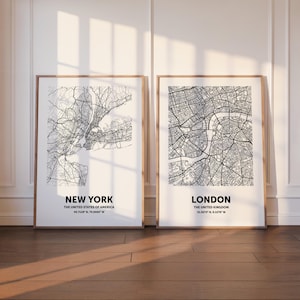 May include: Two framed city map prints. The left print features a detailed black and white map of New York City, with the text "NEW YORK" and coordinates. The right print shows a map of London, with the text "LONDON" and coordinates.