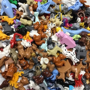 Può includere: Una grande collezione di figurine di animali di plastica colorate. Le figurine sono fatte di mattoncini Lego e includono una varietà di animali, come un delfino, un maiale, uno scoiattolo, un cane, un gatto e una tartaruga.