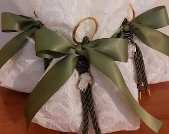 May include: Three white lace favor bags with olive green satin ribbon bows and gold rings. Each bag has a green rope tassel with a white cross charm.