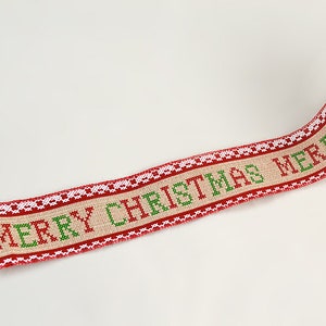 May include: A roll of beige burlap ribbon with red and green embroidered text that reads "Merry Christmas".