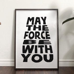 May include: Black and white print with the text "May the Force be with you" in a stylized font. The text is surrounded by small white stars.