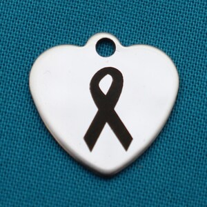 May include: A silver heart-shaped charm with a black ribbon engraved on it.