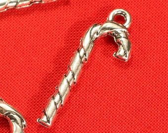May include: Silver-toned candy cane charms with a twisted design. The charms are on a red background.