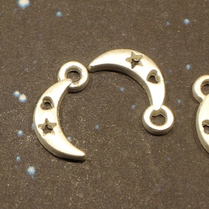 May include: Three silver charm pendants shaped like crescent moons with cut-out stars and hearts.