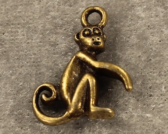 May include: A gold-toned metal charm in the shape of a monkey sitting with its tail curled around its legs.