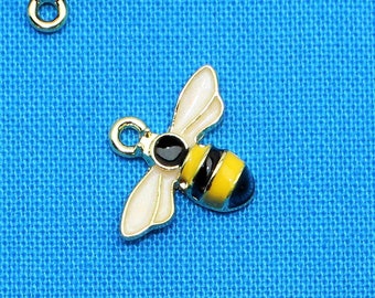 May include: A collection of ten gold bee charms with black and yellow enamel details. The bees are arranged on a blue fabric background.