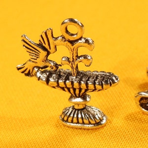 May include: Two silver-toned metal charms, each depicting a dove with an olive branch and a chalice. The charms are intricately detailed and have a vintage aesthetic.