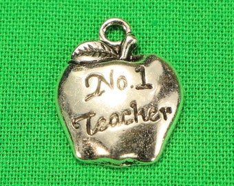 Puede incluir: Encanto de plata con forma de manzana con las palabras "No. 1 Teacher" grabadas.