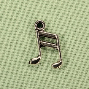 May include: Silver music note charm with a green gemstone accent. The charm is a treble clef with a single note attached to the bottom.