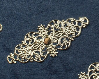 May include: A collection of silver filigree embellishments with a decorative, ornate design. The embellishments are arranged on a dark blue background.