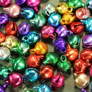 May include: A large assortment of small, colorful metal bells. The bells are in various shades of blue, green, red, purple, gold, and silver. They are all about the size of a dime.