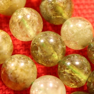 May include: A strand of green and brown gemstone beads. The beads are round and have a smooth, polished finish.
