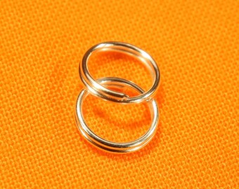 May include: Two silver key rings, one inside the other, on a bright orange background.