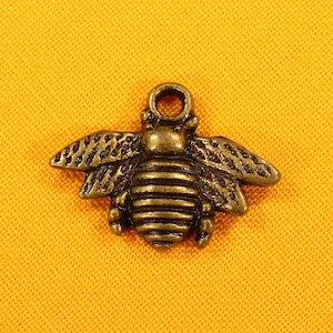 May include: A gold-toned metal bee charm with detailed wings and a segmented body.