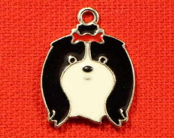 Op de afbeelding: Een zwart-witte hondenbedel met een rode strik. De bedel heeft een zilveren omtrek en een lus om aan een ketting of armband te bevestigen. Het gezicht van de hond is wit met zwarte oren en een zwarte neus.
