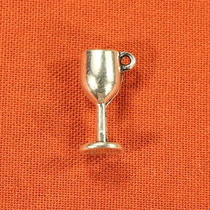May include: Silver charm in the shape of a wine glass. The charm has a loop at the top for attaching to a bracelet or necklace.