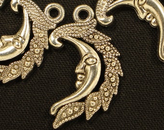 May include: Seven silver metal charms in the shape of a crescent moon with a face on it. Each charm has a leafy design and a loop at the top for attaching to a necklace or bracelet.
