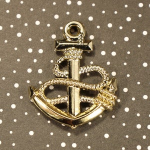 May include: Gold-coloured metal anchor charm with a rope design. The anchor is a nautical symbol of hope and strength.