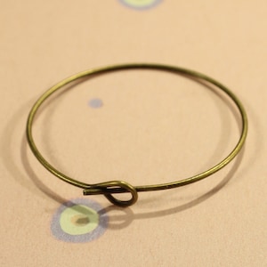 May include: A simple gold-toned metal bangle bracelet with a knotted closure.