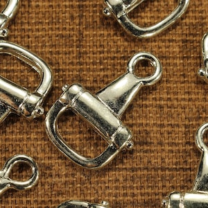 May include: A close-up of silver metal D-rings, commonly used for attaching straps, chains, or other hardware to bags, purses, or other accessories.