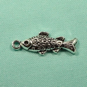 May include: A silver charm in the shape of a fish with a textured surface. The charm has a loop for attaching to a bracelet or necklace.