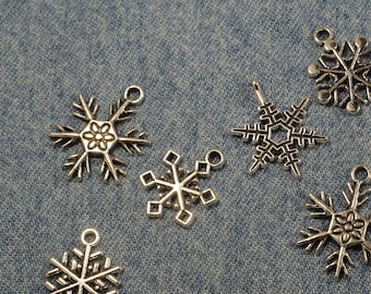 May include: A collection of eight silver snowflake charms with intricate designs. The charms are perfect for adding a touch of winter magic to jewelry, crafts, or home decor.