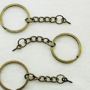 May include: Three antique gold keychains with a circular ring and a chain with a screw clasp.