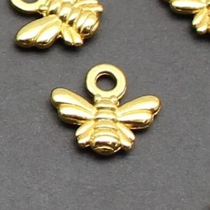 May include: A group of gold bee charms with a loop for attaching to jewelry or other crafts.