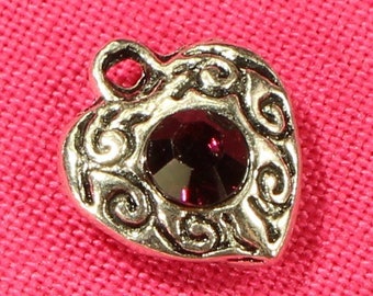 May include: Silver heart charm with an ornate design and a dark purple rhinestone in the center.