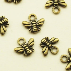 May include: A group of 14 antique gold bee charms with a loop for attaching to jewelry or other crafts.