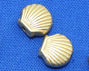 May include: Gold-colored metal seashell beads with a raised design. The beads have a hole in the center for stringing.