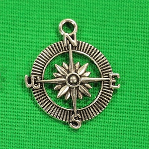May include: Silver compass charm with a starburst design and the letters N, S, E, and W around the edge.