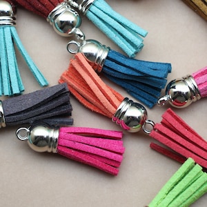 May include: Assortment of colorful leather tassels with silver metal caps. The tassels are in various colors, including teal, blue, orange, pink, red, gray, and green.