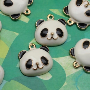 May include: A set of six white panda bear charms with black eyes and ears. The charms have a gold loop for attaching to jewelry or other crafts.