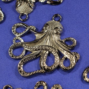 May include: Silver-toned metal octopus charm with detailed tentacles and a textured body. The charm has a loop at the top for attaching to jewellery or other crafts.