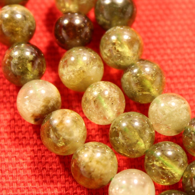 May include: A strand of green and brown gemstone beads. The beads are round and have a smooth, polished finish.